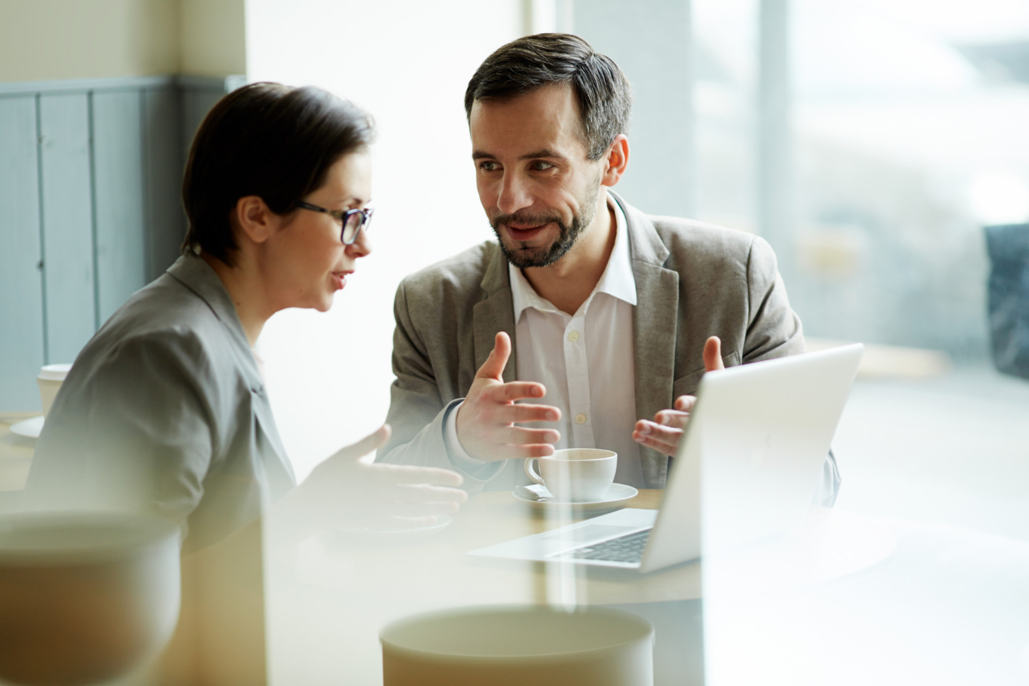 Two people having discussion in front of laptop, having coffee