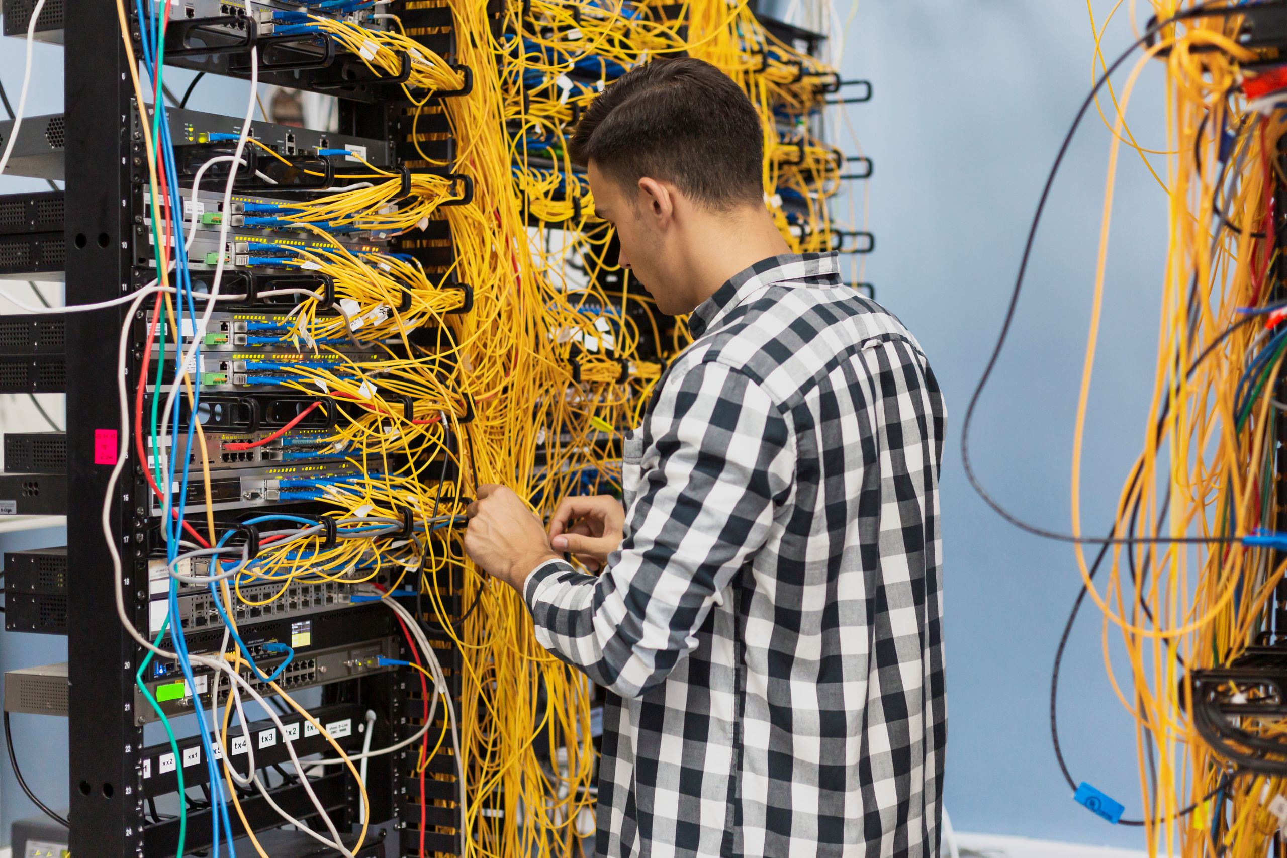 Technician organizing yellow cables on a server rack