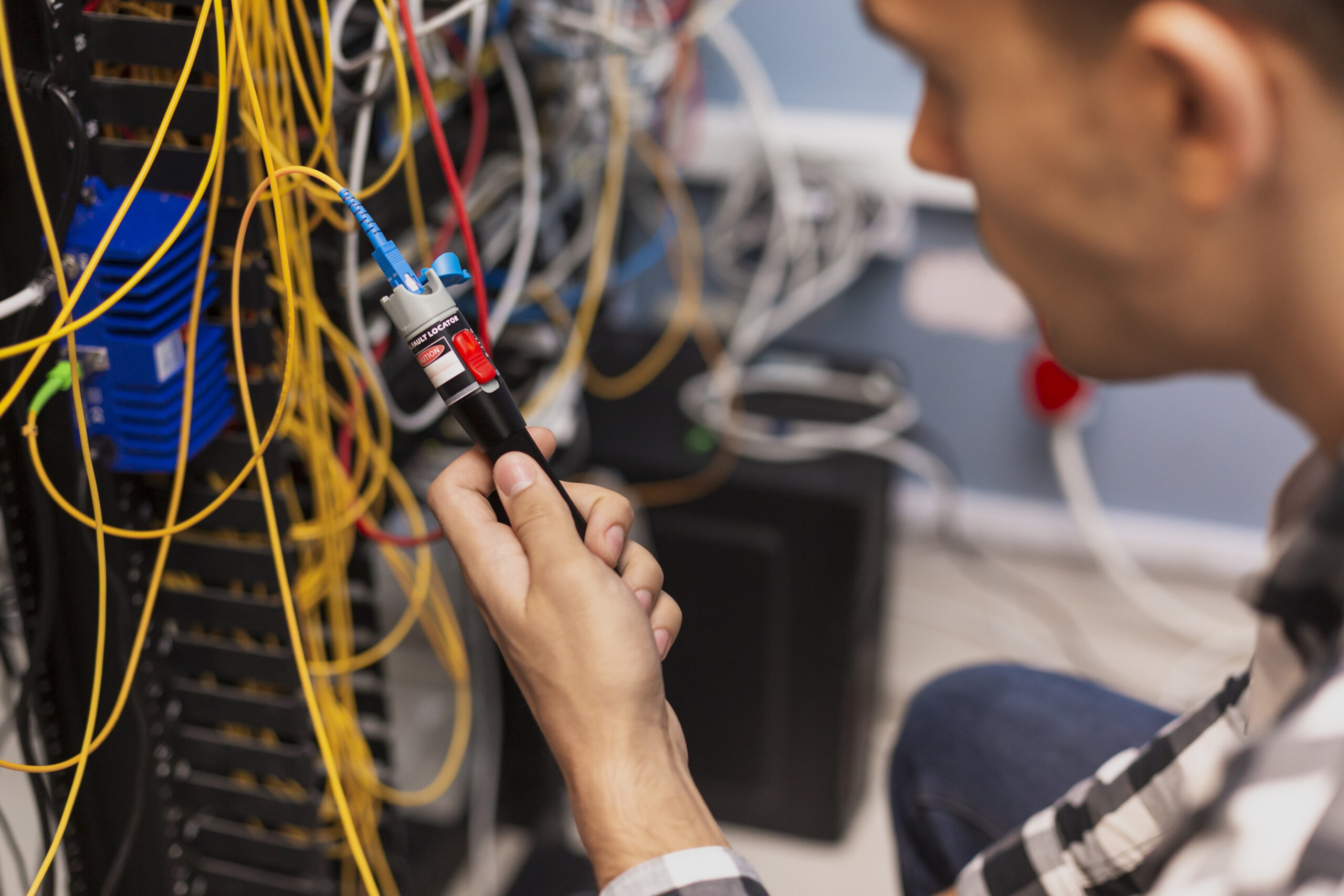 Technician testing wires with a visual fault locator tool.