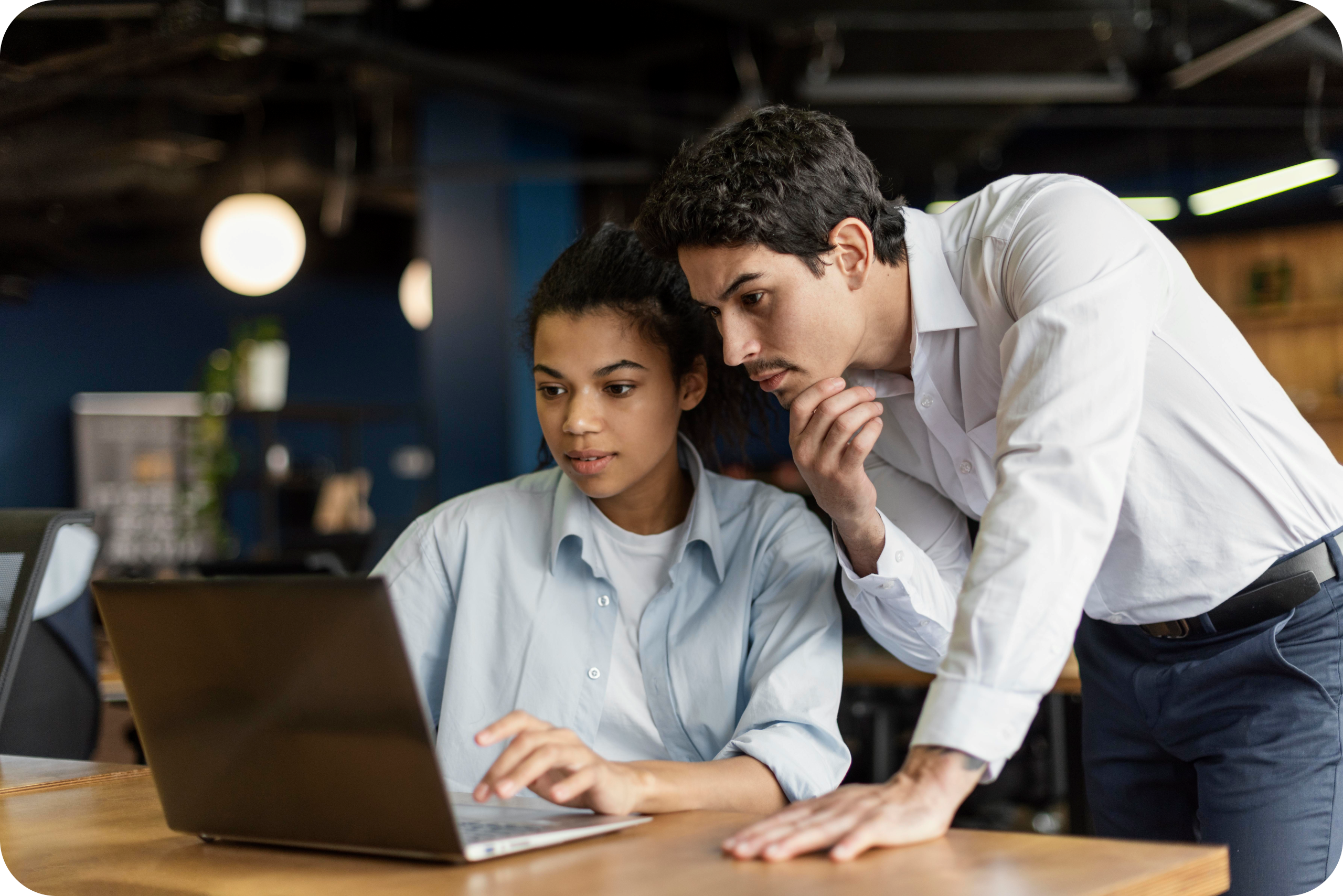 Two coworkers looking at a laptop.